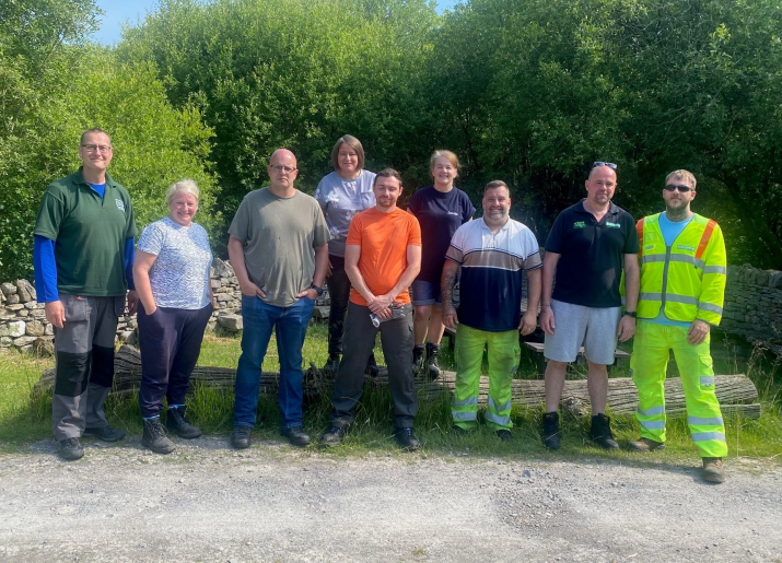 A group of people in work clothes stood in a row and smiling into the camera.