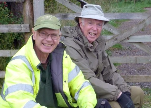 Two men sitting on a straw bale and laughing
