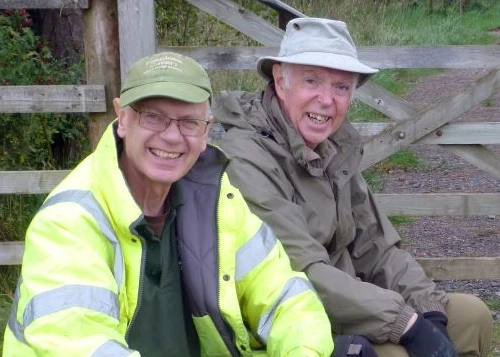 Two men sitting on a straw bale and laughing