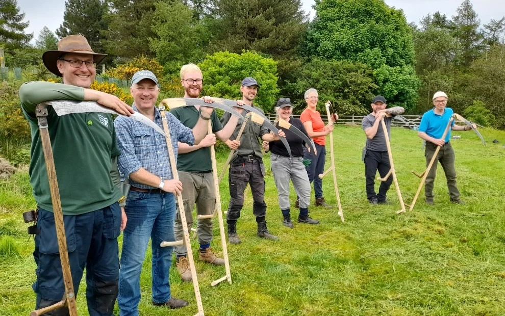 A group of people smiling and holding scythes
