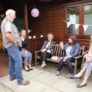 Volunteers talking with a cup of tea, strawberry tart and cake